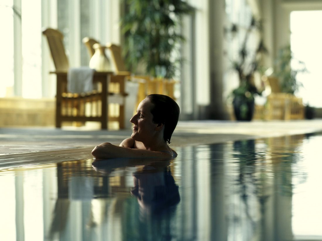 A guest resting at the edge of the indoor pool at Fox Harb'r