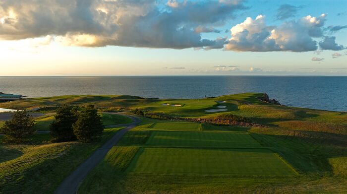 The par-3 12th on the Ocean Course from above the tees, the green and the Northumberland Strait beyond in evening light