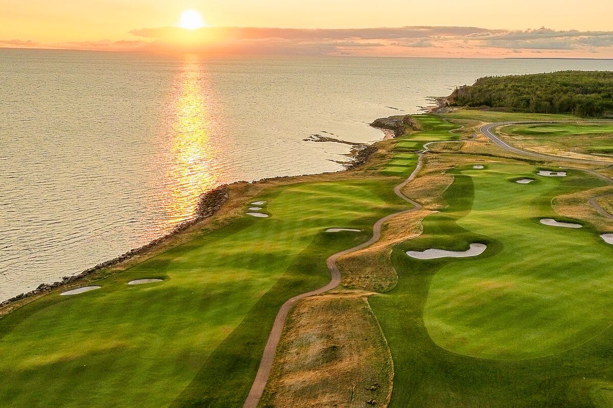 Aerial view of the 18th hole on the Ocean Course at sunset, bunkers across the fairway and the Northumberland Strait alongside