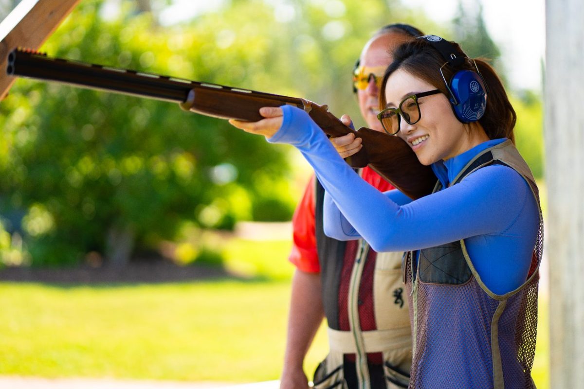 A guest taking aim at the sporting clays range with an instructor beside her
