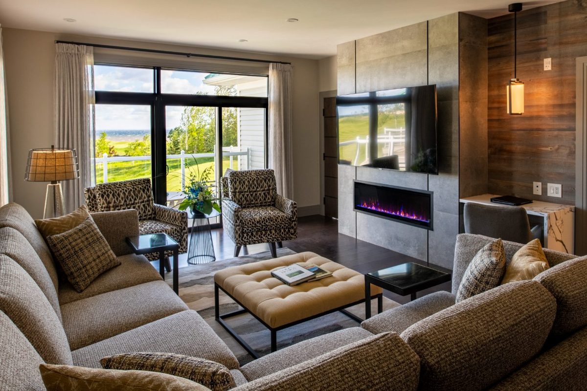 A suite living room with a fireplace and doors opening onto the course